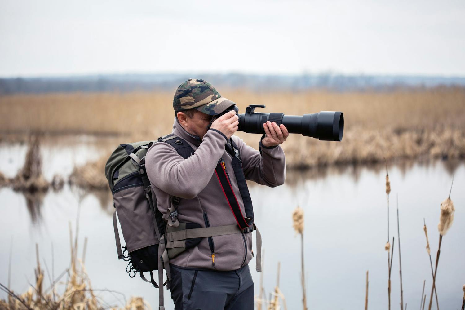 Mandlig fotograf stiller skarpt på sit teleobjektiv i marken